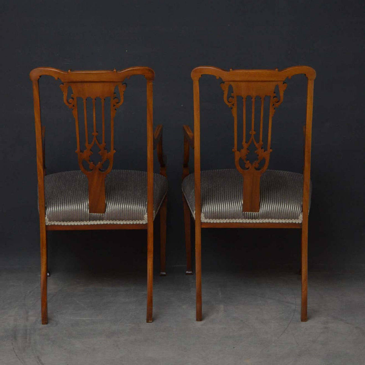 Two wooden chairs with decorative backrests on a dark background