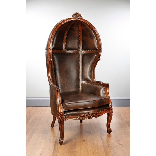 A luxurious dark brown leather armchair with a high umbrella back and a rich mahogany polish finish, featuring intricate wood carvings and a decorative top.
