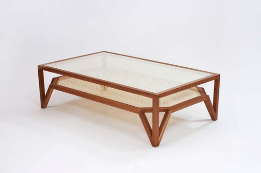 A rectangular Sidqa Mahogany Double-Decker Cane Coffee Table with a clear glass top and a brown wooden frame supported by a patterned cane structure.
