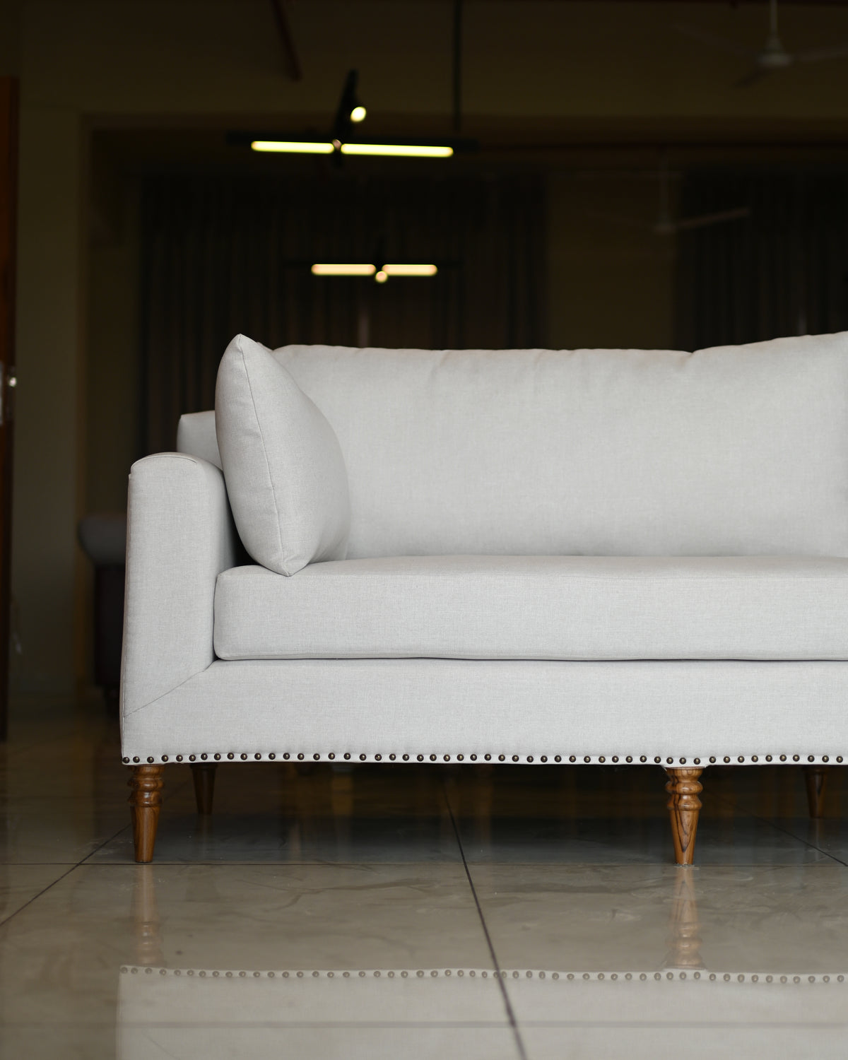 Light gray sofa with wooden legs in a dimly lit room