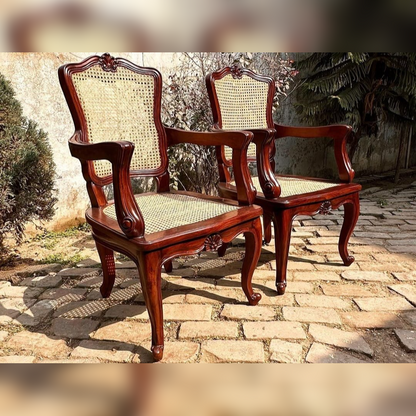 Pair of wooden chairs with wicker seats on a stone patio