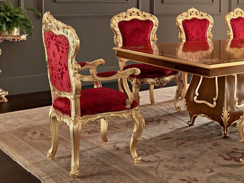 Dining table set with red chairs and gold frames in a formal dining room.