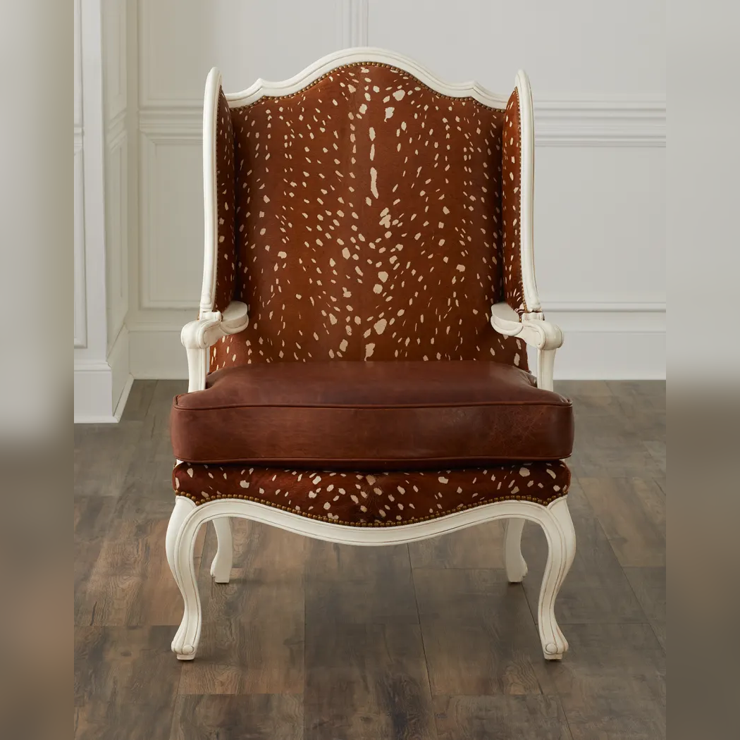 Decorative chair with brown and white patterned backrest and white frame on a wooden floor.