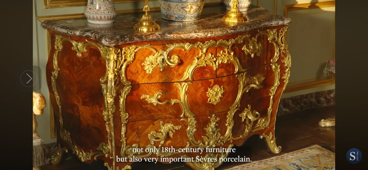 Decorative 18th-century wooden chest with gold accents in an elegant room.