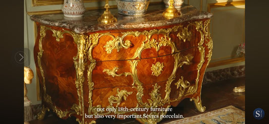 Decorative 18th-century wooden chest with gold accents in an elegant room.