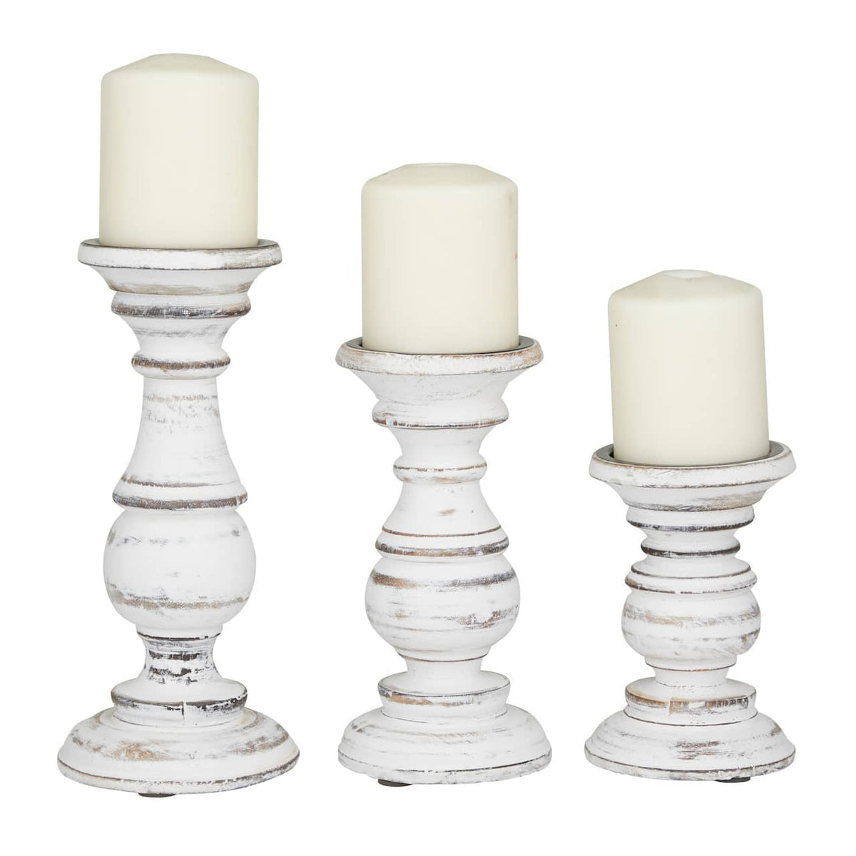 A set of three white candle stands with a weathered texture, in varying heights, each with a candle on top.
