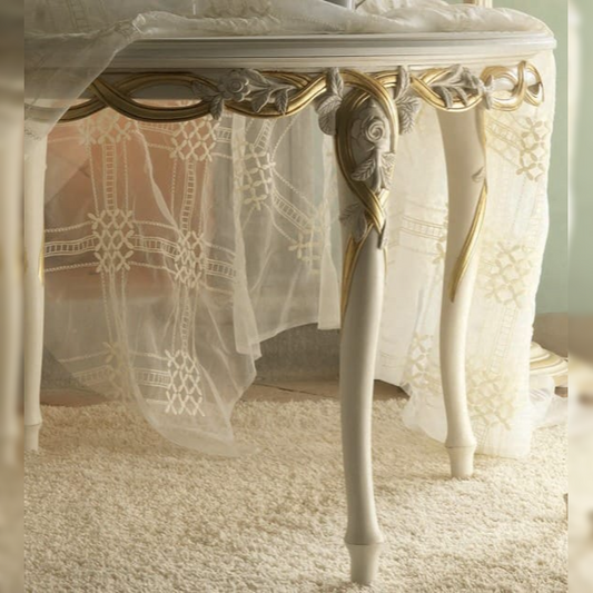 Decorative table with gold accents and sheer white fabric in a softly lit room.