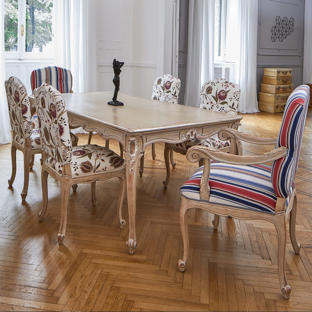 Dining room with a wooden table and patterned chairs on a wooden floor.