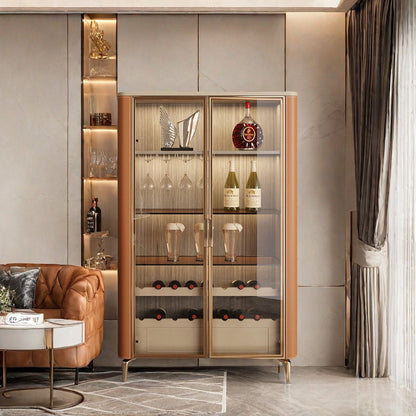 Elegant wooden bar cabinet with glass doors, showcasing wine bottles and glasses, placed in a room with a leather sofa and a side table.