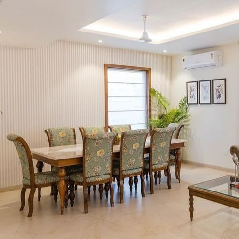 Dining room with wooden table and chairs with floral patterns, air conditioner on wall.