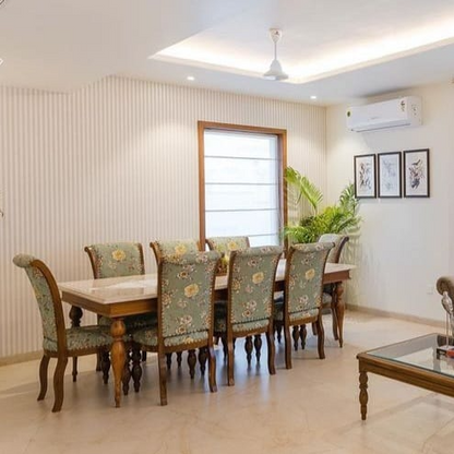 Dining room with wooden table and chairs with floral patterns, air conditioner on wall.