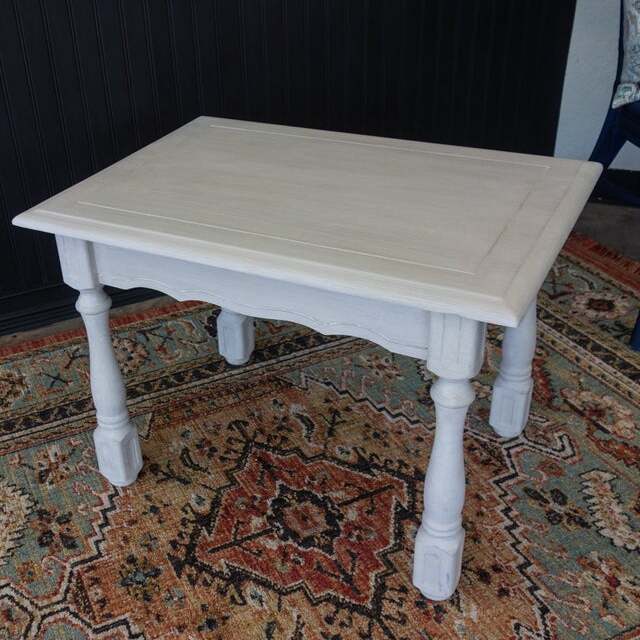 White wooden table on a patterned rug with a dark background