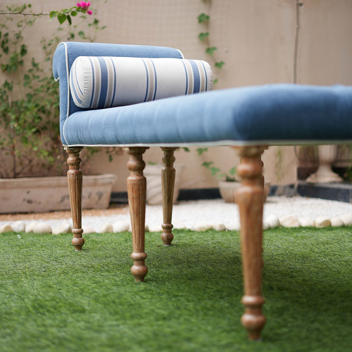 Blue cushioned chair with wooden legs on a grassy area