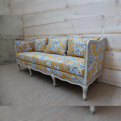 Decorative sofa with yellow and blue floral pattern in a room with wooden walls.