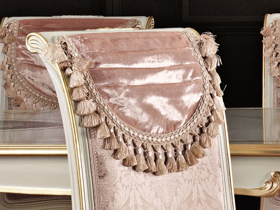 Decorative pink chair with tassels and intricate details in a formal setting.