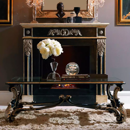 An elegant black and gold glass-top coffee table with intricate gold carvings on the legs, placed on a fluffy white rug.