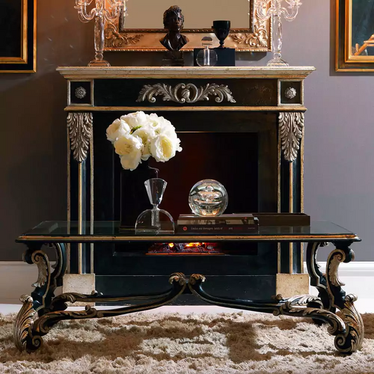 An elegant black and gold glass-top coffee table with intricate gold carvings on the legs, placed on a fluffy white rug.