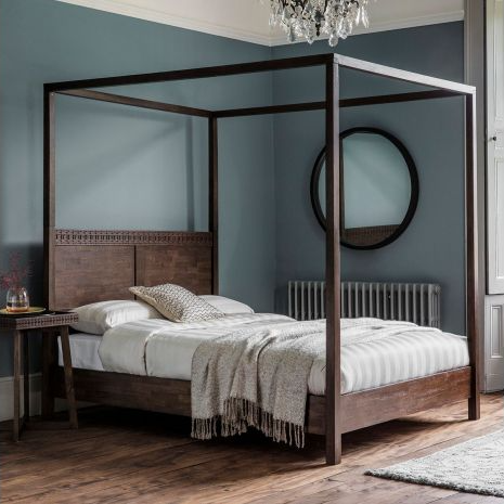 Wooden canopy bed in a bedroom with blue walls and a chandelier.
