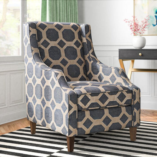A gray and gold geometric patterned armchair with teak mahogany wooden legs, positioned in a room with a striped rug and green curtains.