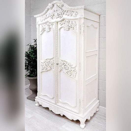 White ornate wardrobe in a room with light gray walls and a plant.