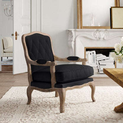 A black upholstered Sidqa Vintage Elegance Armchair with a distressed French wooden frame, placed in a room with a white rug and fireplace in the background.