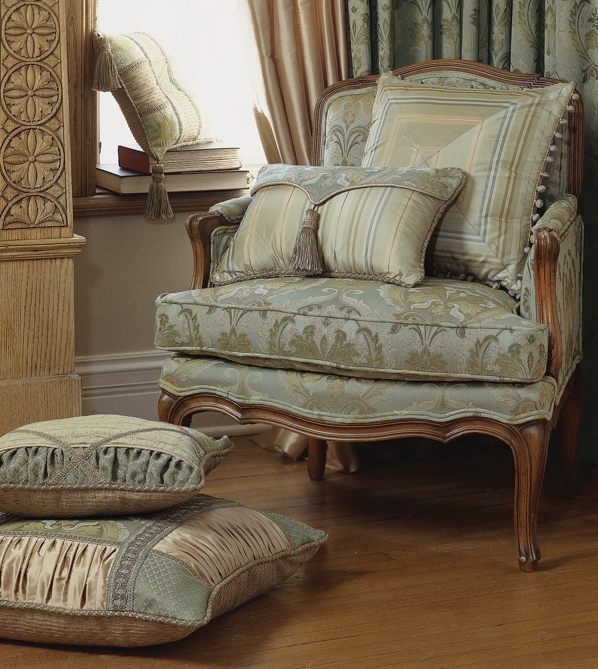 An exquisite pastel green French finish armchair with teak wood frame, accompanied by matching pillows and a footstool, set against a room with elegant decor.