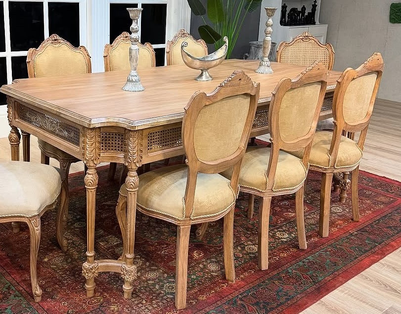 Wooden dining table with chairs in a room with a large window.