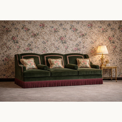 Green velvet sofa with floral cushions against a floral wallpapered wall.