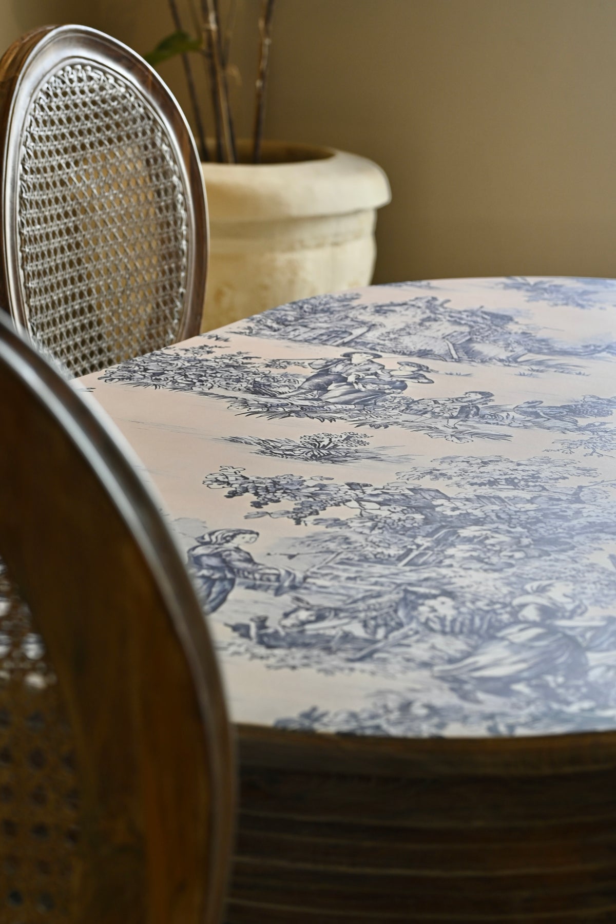 Table with a blue and white patterned tablecloth and wicker chairs.