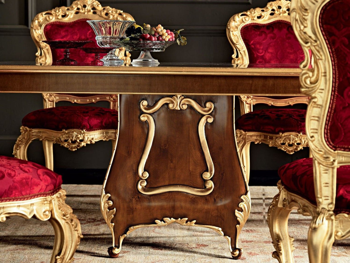 Decorative dining table with ornate gold legs and red chairs in a formal setting.