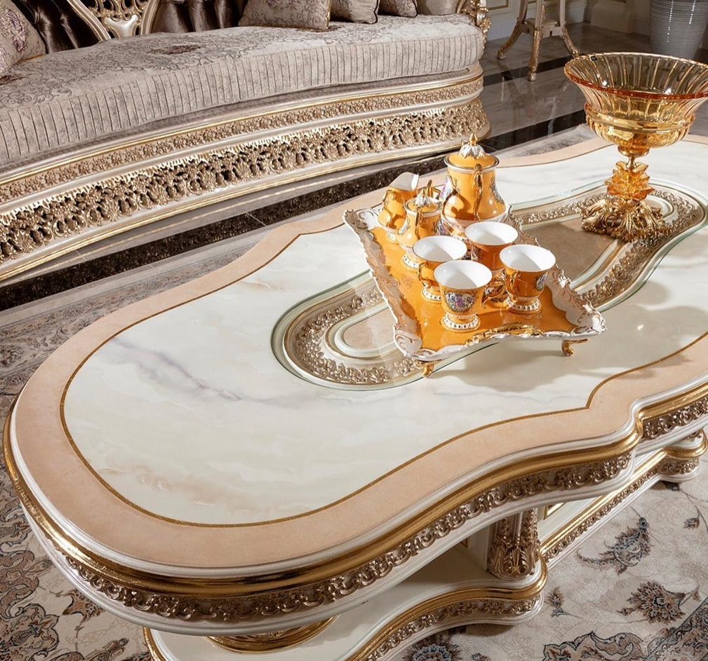 Decorative coffee table with ornate design and gold accents in a room setting.