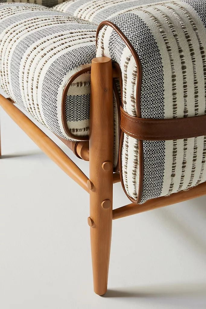 Close-up of a chair with striped cushion and wooden frame on a light background