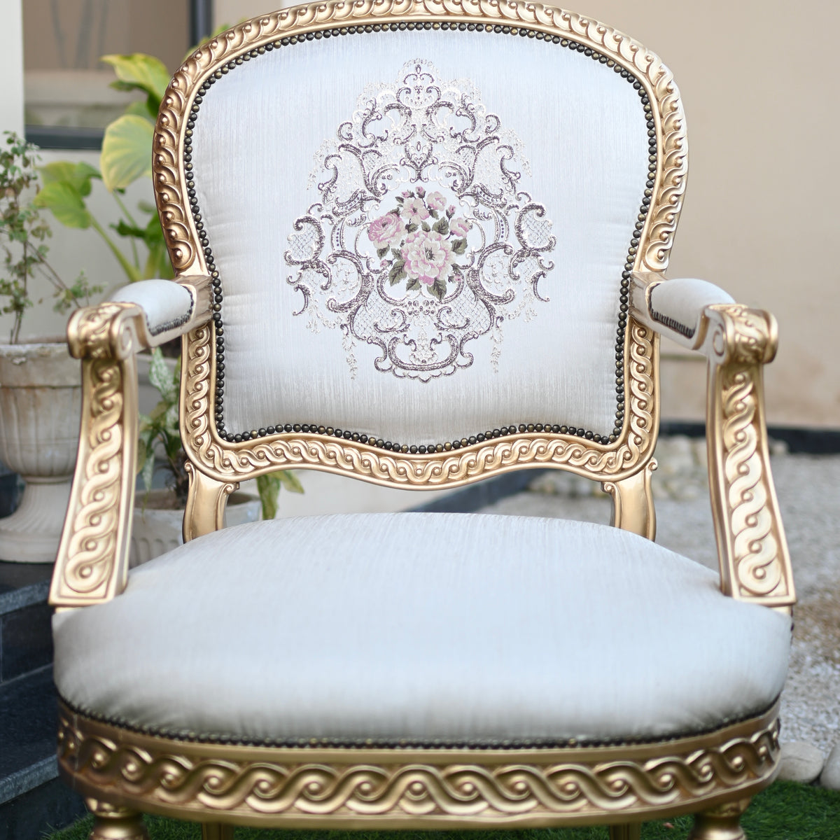 Decorative chair with gold frame and white cushion featuring floral embroidery.