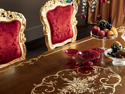 Decorative table setting with red chairs, fruit, and jewelry on a wooden table.