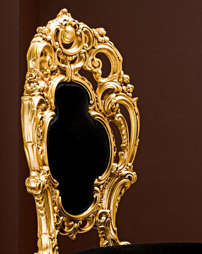 Decorative gold mirror with intricate designs on a dark background