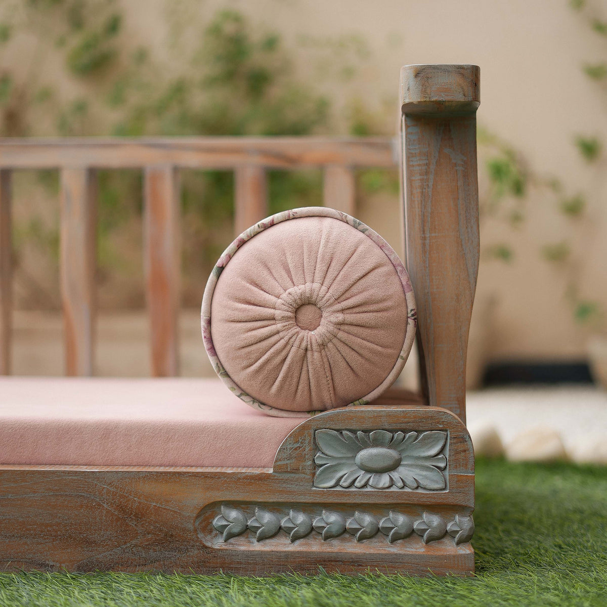 Decorative wooden chair with a pink cushion on a grassy area