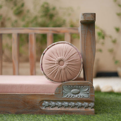 Decorative wooden chair with a pink cushion on a grassy area