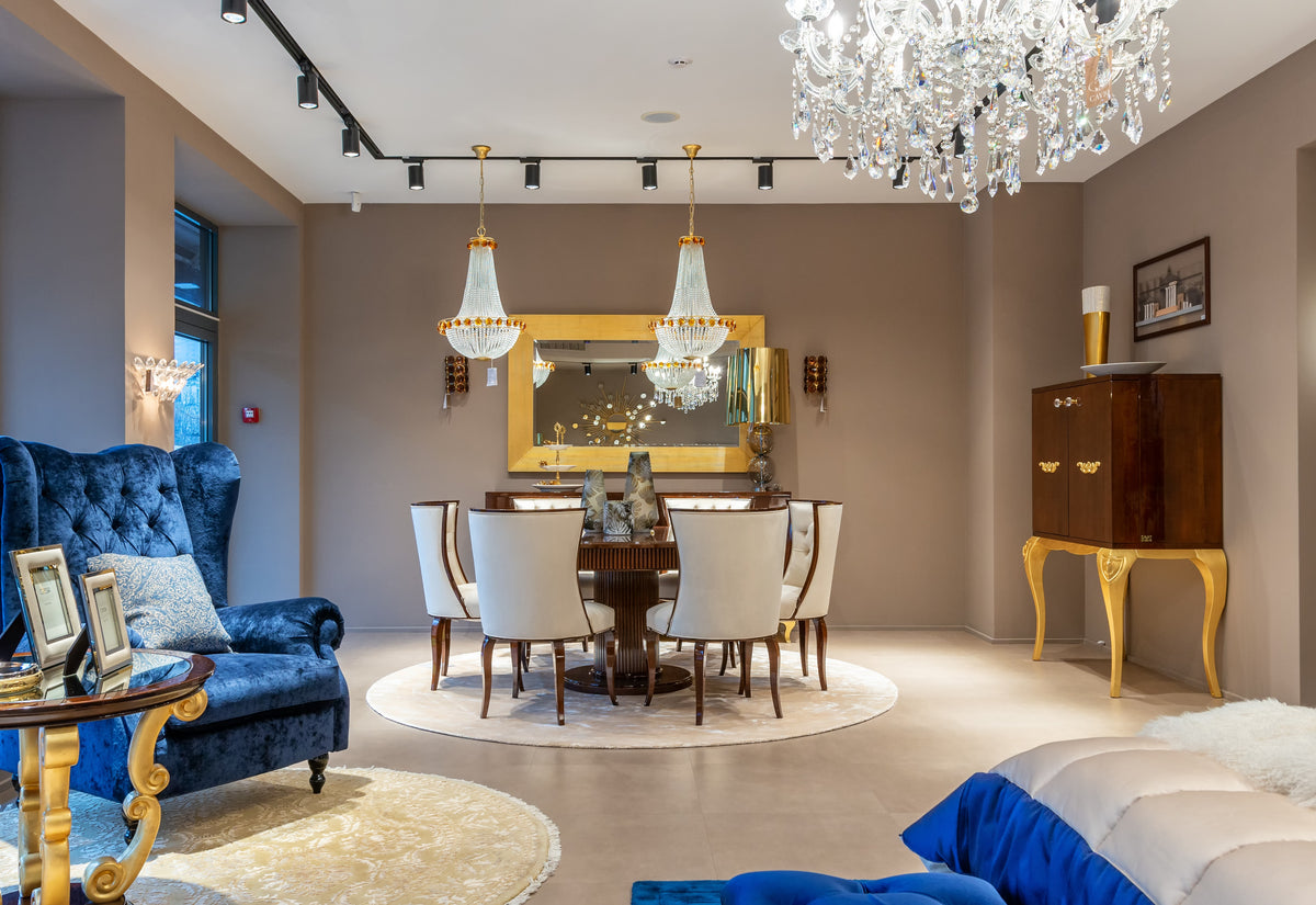 Elegant dining room with a chandelier, blue armchair, and round table.