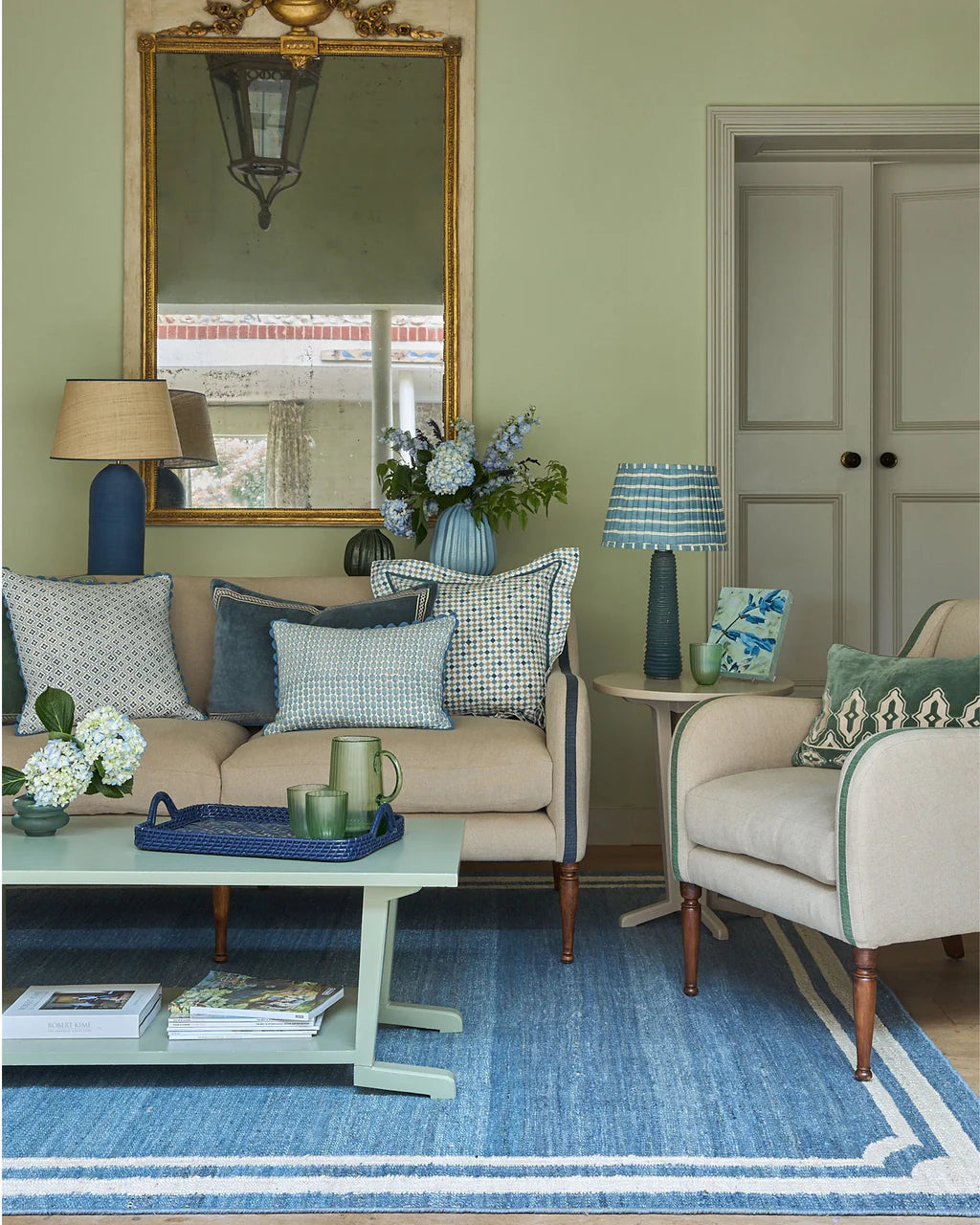 Living room with beige sofa, armchair, and decorative items on a blue rug.