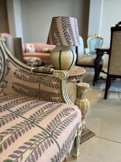 Decorative lamp with patterned shade on a ornate chair in a room with furniture.
