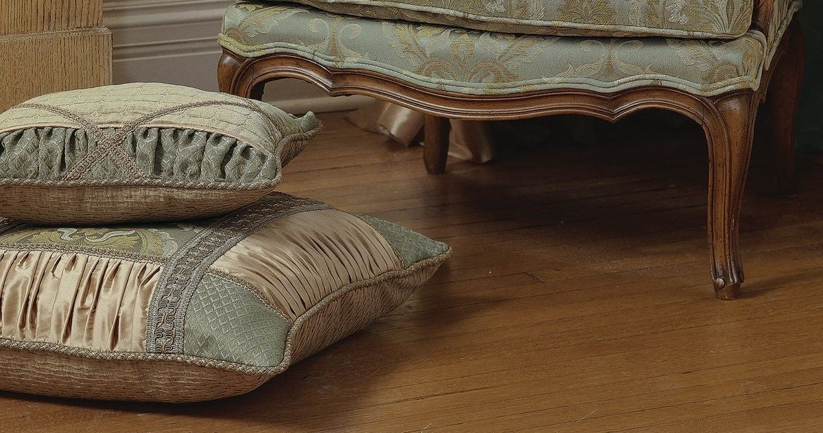 Decorative pillows on a wooden floor with a piece of furniture in the background