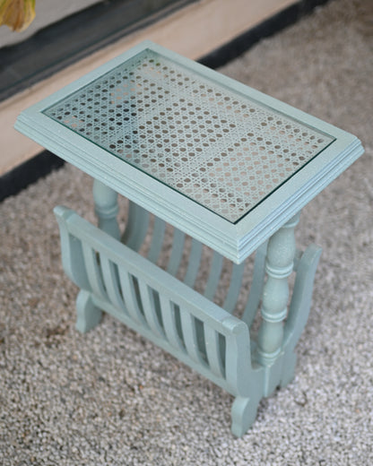 Small light blue side table with a woven top on a carpeted floor.