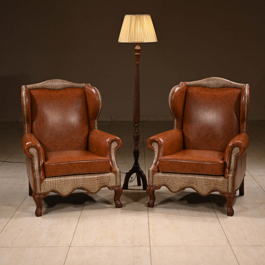 Two brown leather armchairs with wicker backrests and sides, placed on a tiled floor with a lamp in the background.