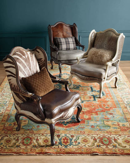 Three ornate armchairs with patterned cushions on a decorative rug against a blue wall.