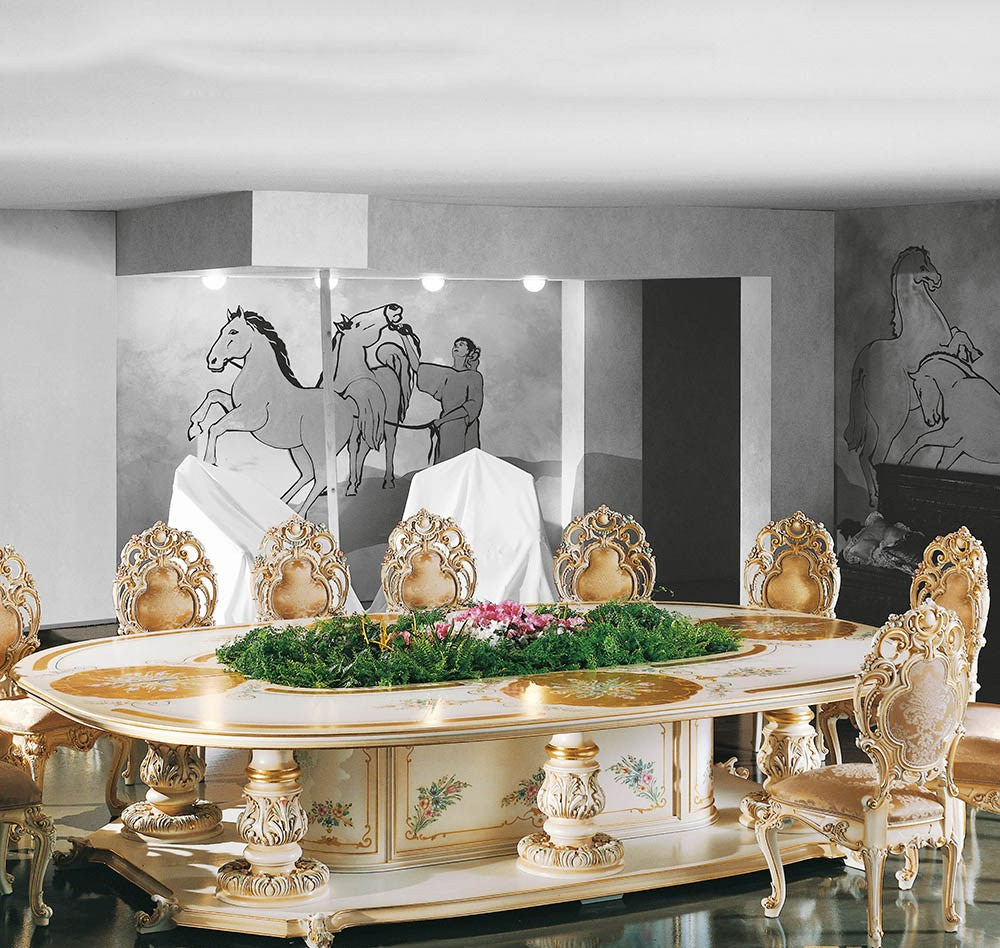Decorative dining table with ornate chairs in a room with artistic wall pieces.
