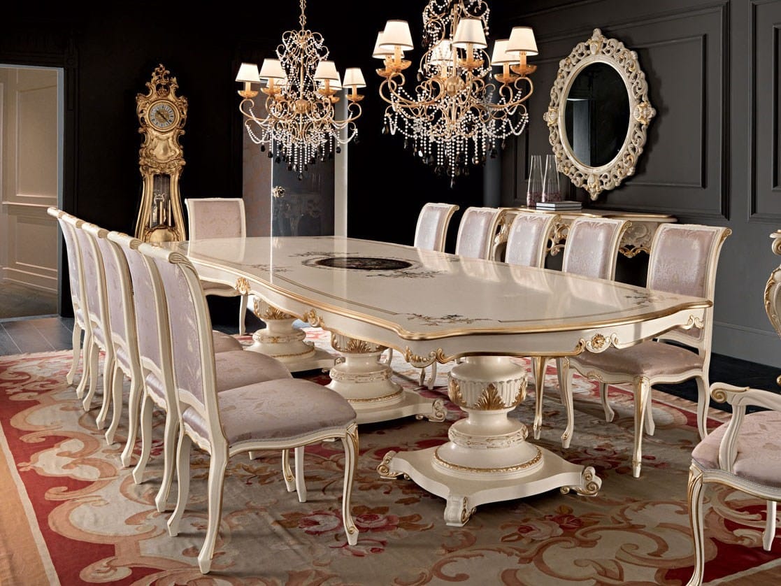 Elegant dining room with a large ornate table and chairs, chandeliers, and a grandfather clock.