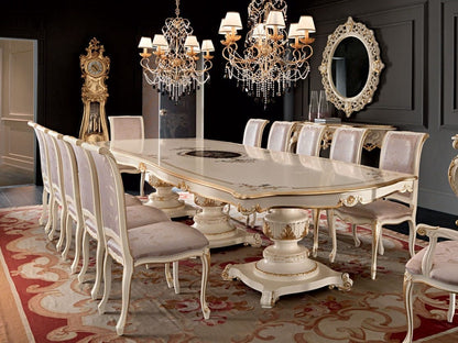 Elegant dining room with a large ornate table and chairs, chandeliers, and a grandfather clock.
