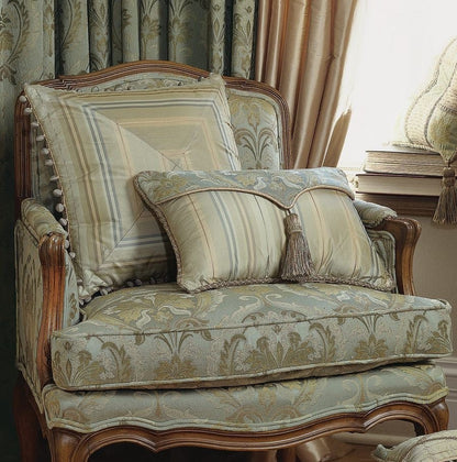 Decorative armchair with patterned cushions in a room with curtains and books.