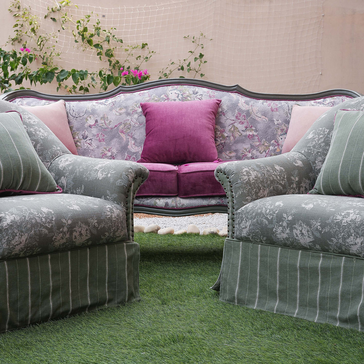 Floral-patterned sofa with pink cushions on a grassy area
