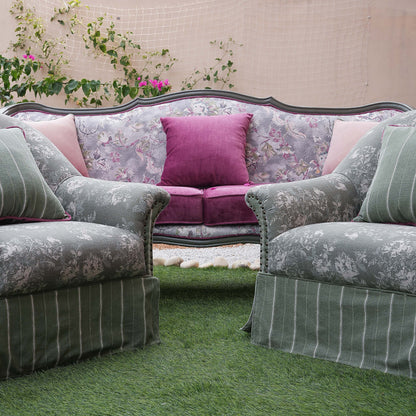 Floral-patterned sofa with pink cushions on a grassy area